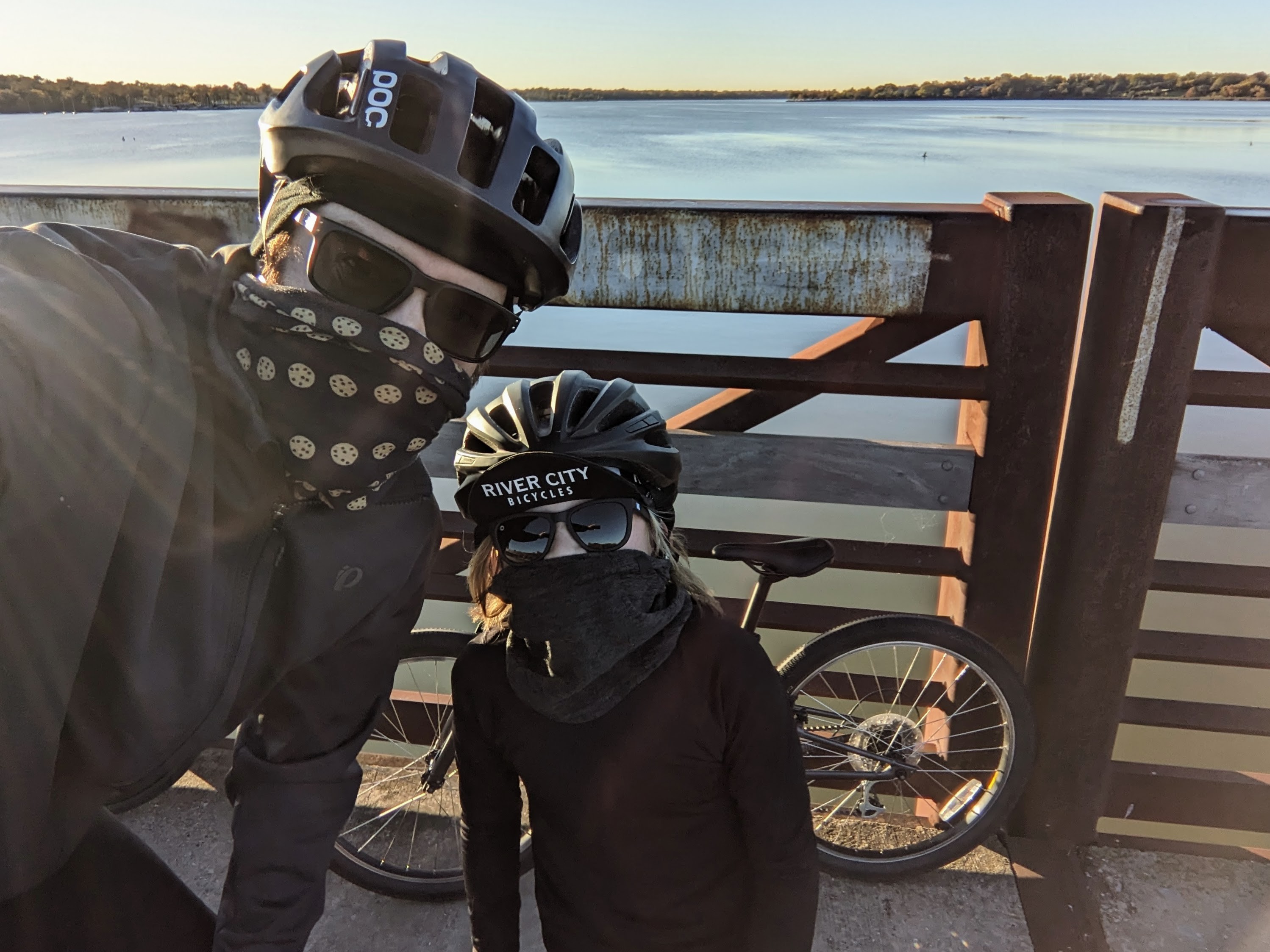 Two cold cyclists, aged 48 and 9, taking a selfie on a bridge over a lake.